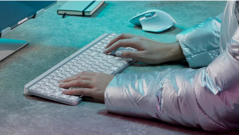 Klawiatura Logitech MX Keys S grafitowa grafika przedstawia ręce kobiety na klawiaturze przed laptopem obok myszka notatnik