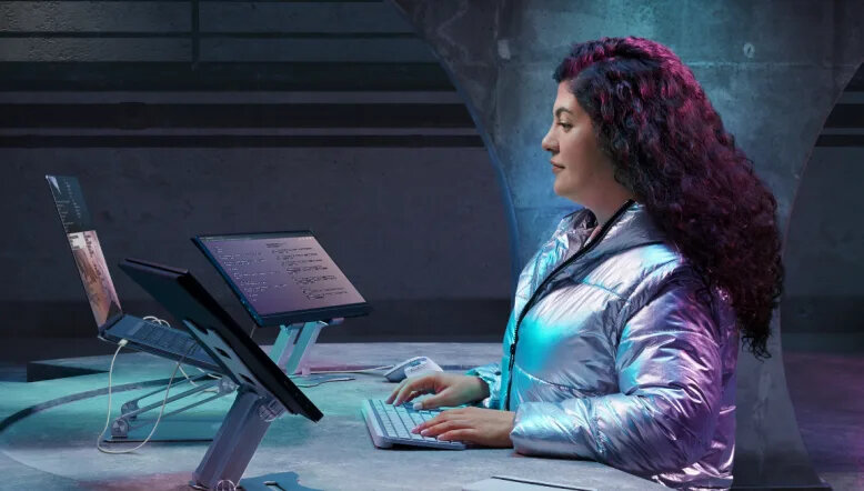 Klawiatura Logitech MX Keys S grafitowa grafika przedstawia kobietę siedzącą przy biurku przed laptopem klawiaturą i dwoma tabletami