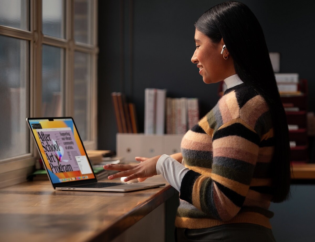 Laptop Apple MacBook Air 2023 15.3 Retina M2 8/512GB Srebrny na stole obok stojącej kobiety