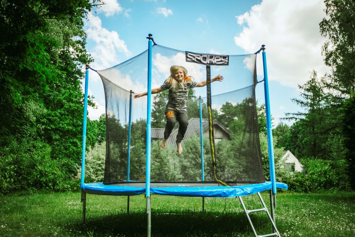 Trampolina ogrodowa Spokey Jumper 244 cm czarna grafika przedstawia dziecko skaczące na trampolinie